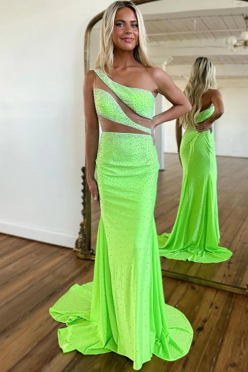 Model wearing a sparkly green one-shoulder mermaid prom dress with cutout details and beading.