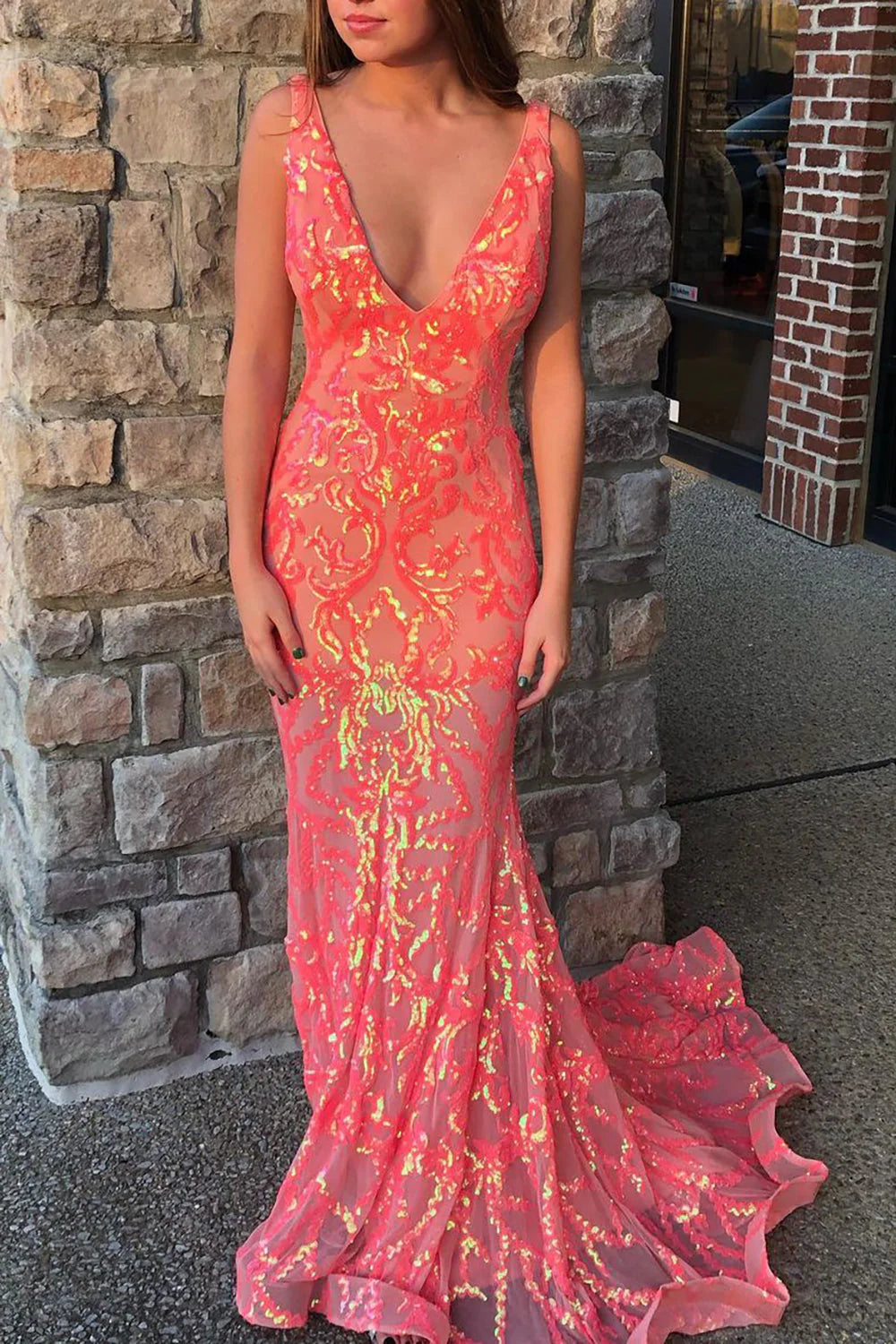 Close-up of a sparkly coral mermaid prom dress, highlighting the deep V-neckline and tight sequin embellishments.