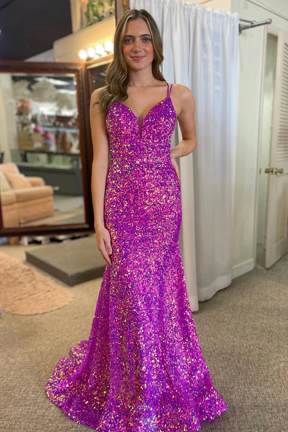 Woman wearing a sparkly purple mermaid prom dress with double spaghetti straps and sequins, full length view.