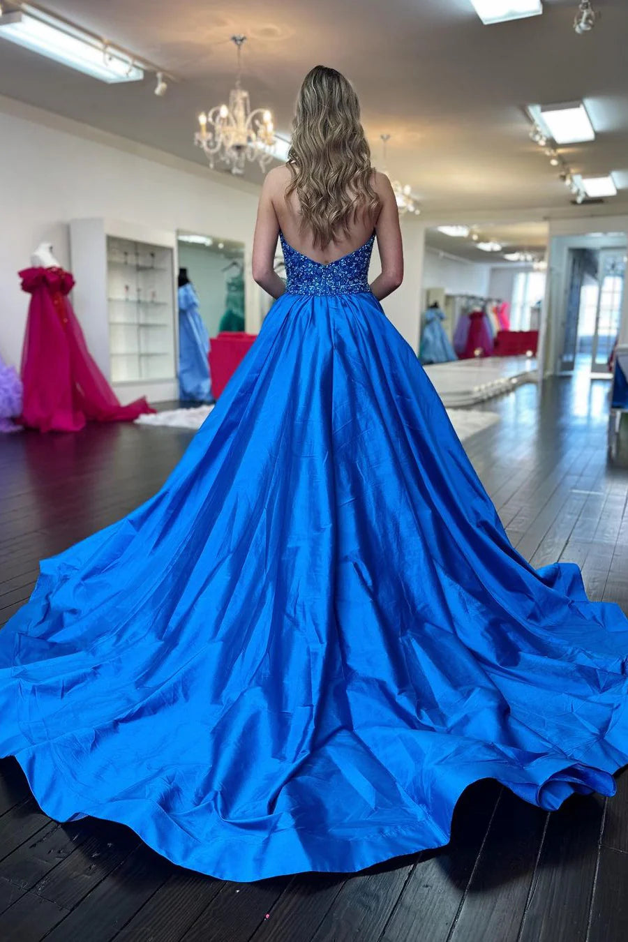Model in blue A-line halter deep V-neck sequin satin prom dress with train, front view.