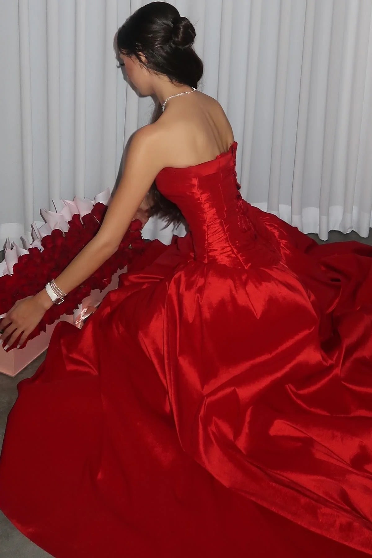 Front view of a woman in a red strapless A-line pleated formal gown.