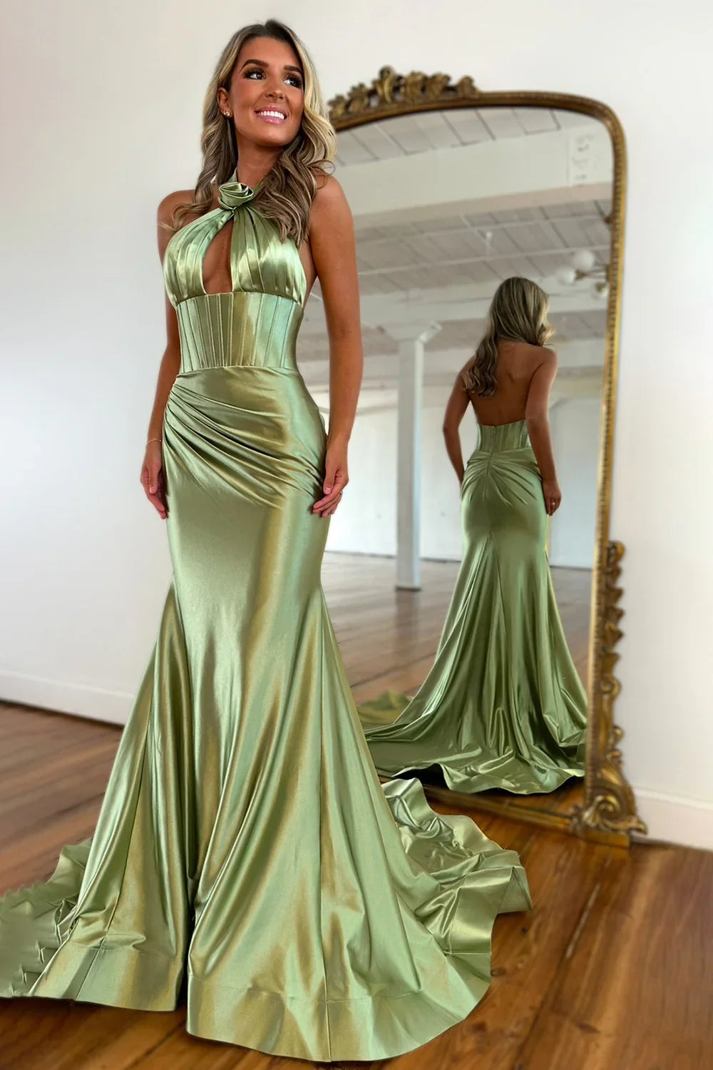 A woman wearing a long, elegant mermaid halter neck backless satin prom dress with a sweep train.