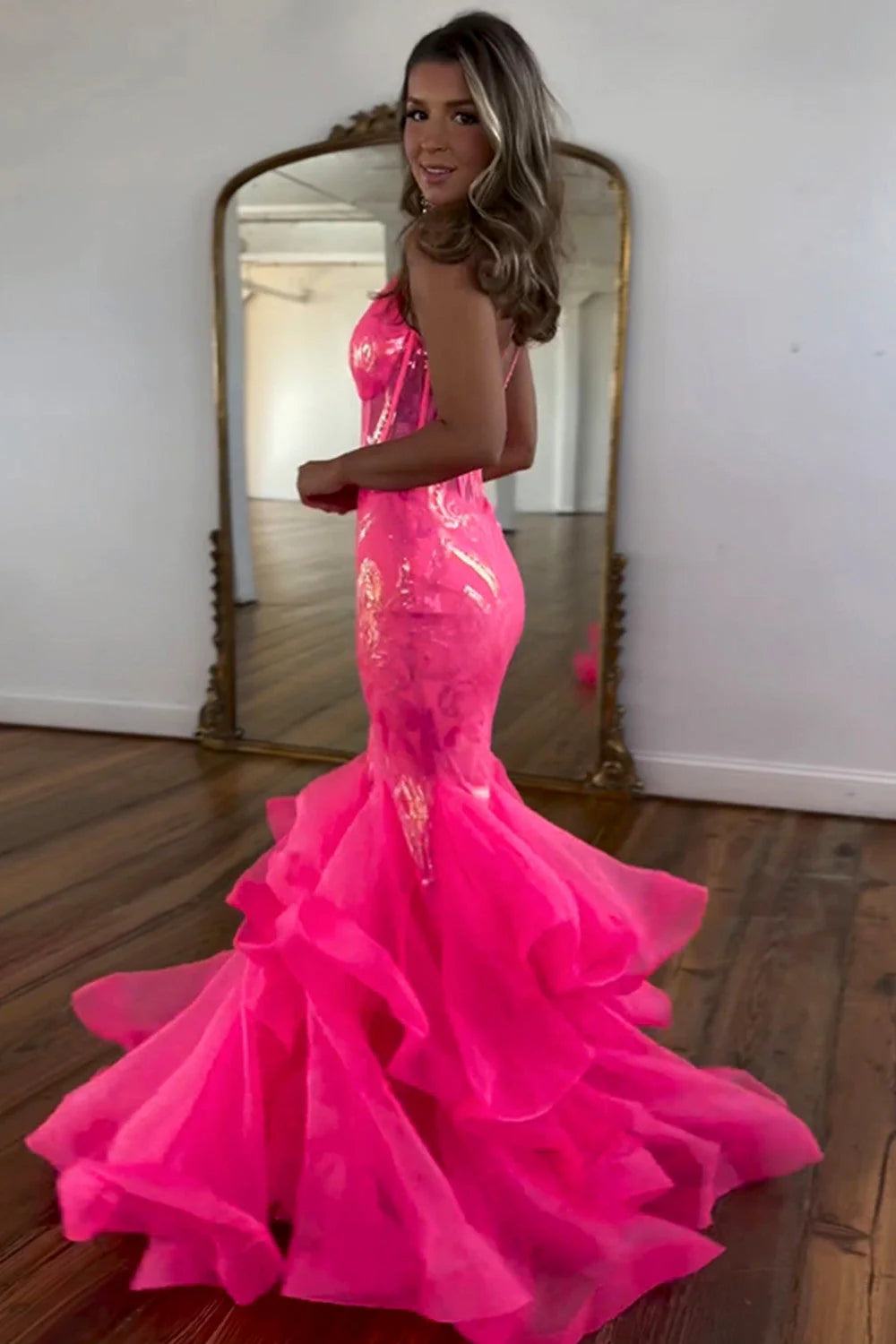 Side profile of hot pink bodycon mermaid gown, highlighting ruffles.